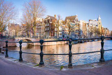 Tipik Amsterdam evlerinin manzarası ve gün batımında kanal üzerinde bir köprü