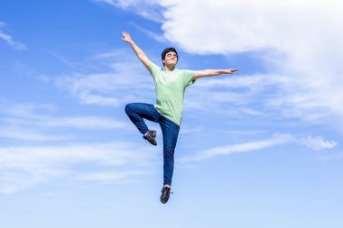 Genç adam sevinçle mavi gökyüzüne atlıyor