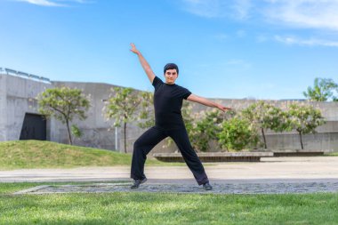 Dinamik genç adam parkta kollarını açmış poz veriyor.
