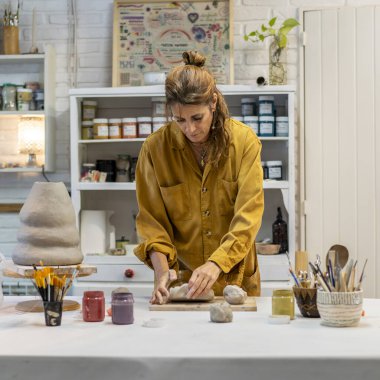 Çömlek atölyesinde kil şekillendiren sanatsal açıdan yetenekli bir kadın.