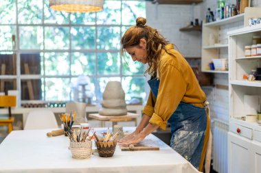 Çamuru tutkuyla şekillendiren sanatçı kadın.