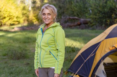 Doğayı keşfeden mutlu sarışın bir kadın, manzaralı bir gülümsemeyle.