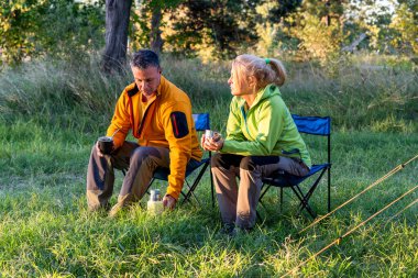 Erkek ve kadın açık havada sıcak içeceklerin tadını çıkarıyorlar.