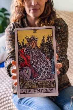 Tarot okuyucusunun elinde tuttuğu dev bir Tarot kartının yakın çekimi.