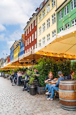 Nyhavn Kanal kenarındaki kafede güneşli bir öğleden sonranın tadını çıkaran insanlar.