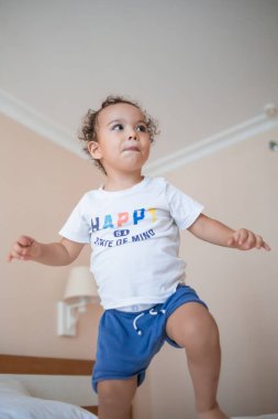 Ebeveyn odasında ebeveyn yatağında zıplayan komik mutlu çocuk.