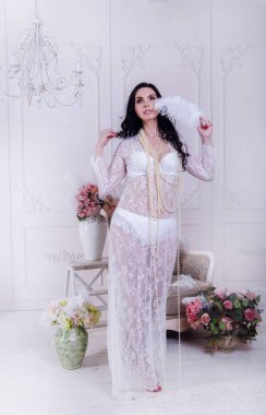 Genç bir esmer, kadın iç çamaşırı giymiş ve özel bir elbise giymiş. Etrafı muhteşem bir çiçek dekoru ile çevrili.. 