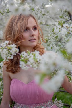 Çiçek açan bahçede bir kızın portresi. Çiçek açan ağaçlar, geleneksel Asyalı, seyahat, mevsimlik nisan arkaplanı.