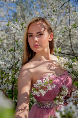 Çiçek açan bir bahçede güzel bir gece elbisesi giymiş Asyalı bir kızın portresi. Çiçek açan ağaçlar, Japon Hanami Sakura Festivali seyahat, mevsimlik.