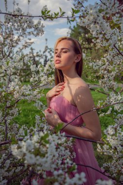 Çiçek açan bir bahçede güzel bir gece elbisesi giymiş Asyalı bir kızın portresi. Çiçek açan ağaçlar, Japon Hanami Sakura Festivali seyahat, mevsimlik.