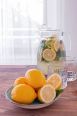 Bardakta limonata ve beyaz arka planda bir sürahi. Yaz ferahlatıcı içecek. Limonlu soğuk detoks suyu