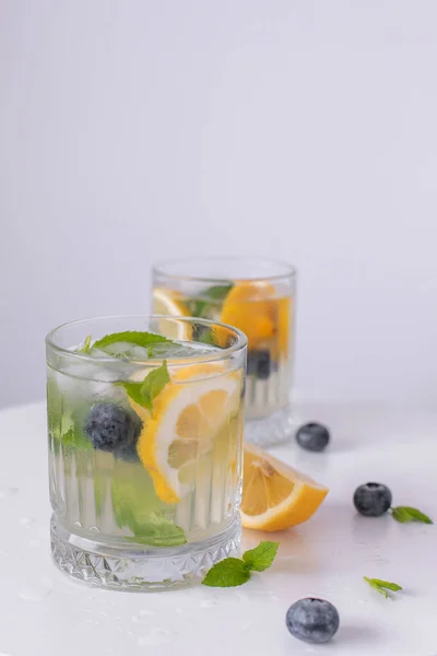 柠檬水放在杯子里 柠檬放在白色的背景上 夏天清爽的饮料 柠檬冷解毒水 — 图库照片