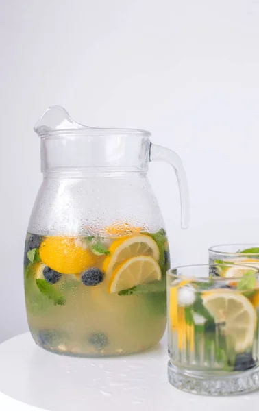 stock image lemonade in a glass and a jug on a white background. Summer refreshing drink. Cold detox water with lemon