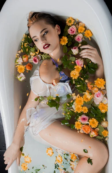 stock image Top view of a sexy woman in lingerie in a bath with flowers and petals.