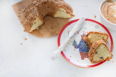 Kırmızı tabakta taze kurabiyeler ve bir fincan kapuçino. Beyaz arka planda yemek ve Noel havası