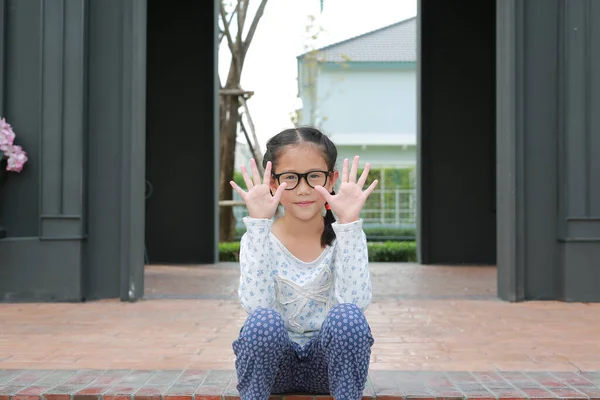 Asyalı Küçük Kız Gözlük Takıyor Bahçenin Bahçesinde Otururken Parmak Kameraya — Stok fotoğraf
