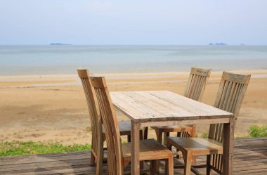 Boş ahşap masa ve sahildeki restoranlarda sandalyeler..