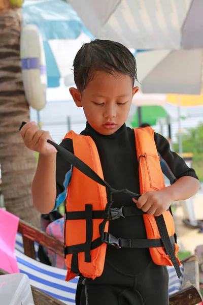 Asian boy wearing life jacket before playing in pool. Kid with life vests. Water safety for children.