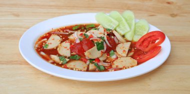 Ahşap arka planda beyaz tabakta baharatlı domuz sosisi salatası - Tayland yemeği.