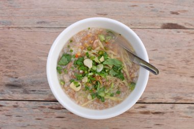 Pirinç lapası, kıyma, sarımsak, kişniş, biber, taze soğan ve ahşap masa arkasında zencefil. Üst görünüm.