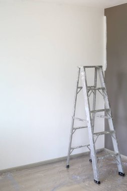 Yeni evin boş odasındaki alüminyum merdiven. Teknisyenlerin daha yüksek işlerde kullanması için. Kopyalama alanı olan resim