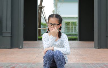 Burnunda parmak olan Asyalı bir kız çocuğu burun deliğini karıştırıyor. Çocuk sümüğü aldı..