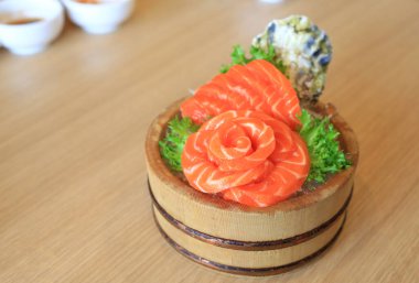 Salmon slices Sashimi fillet in wood bucket on wood table background. Traditional Japanese food.