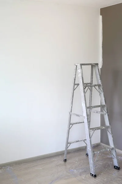 新房屋空房间中的铝梯供技师用 以获得更高的职位 带有复制空间的图像 — 图库照片