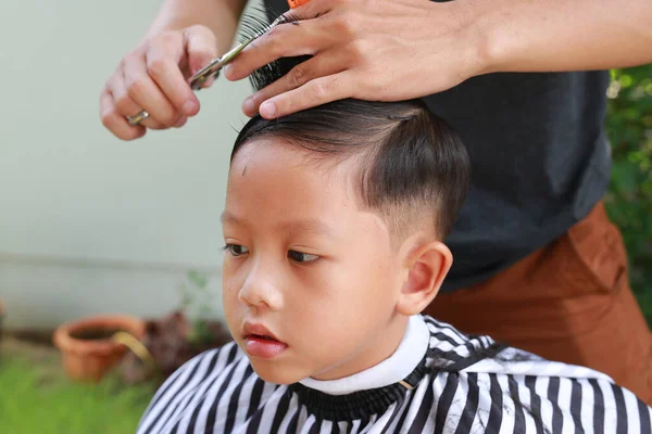 在花园里用理发师剪刀剪头发的亚洲小男孩 — 图库照片