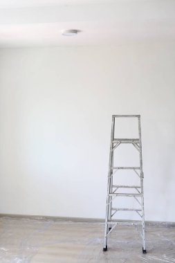 Yeni evin boş odasındaki alüminyum merdiven teknisyenlerin daha yüksek işlerde kullanması için..