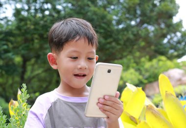 Parkta akıllı telefon kullanan Asyalı küçük çocuk..