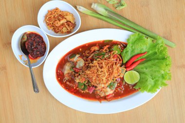 Baharatlı salatanın içinde istiridye ve ahşap arka planda kırmızı biber ve kızarmış soğan. Tayland usulü yemek. Üst görünüm.