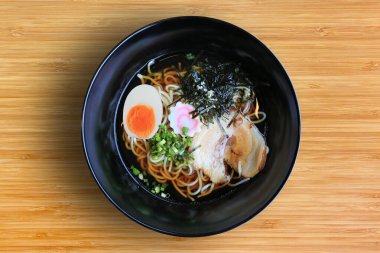 Chashu Pork 'lu Shoyu Ramen eriştesi, yosun ve bambu ahşap arka planda kaynamış yumurta..
