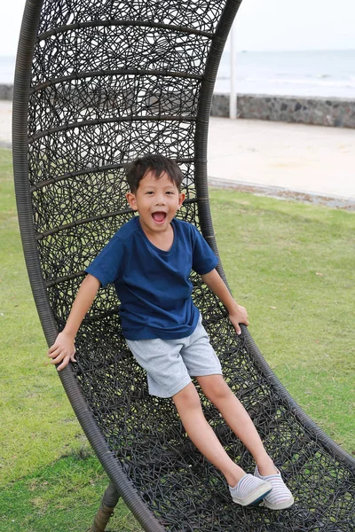 Portrét Malého Asijského Chlapce Leží Kruhovém Ratanovém Křesle Zahradě Pobřeží — Stock fotografie