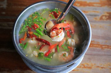 Tom yum goong ya da baharatlı karides çorbası ahşap masa arkasında sıcak ve ekşi. Tayland geleneksel mutfağı.
