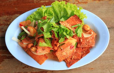 Kurutulmuş baharatlı mürekkep balığı salatası, kaju fıstığı ve ahşap masada taze sebzeler. Tayland tarzı yemek..