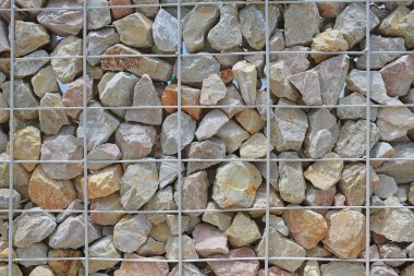 Arka planda çelik parmaklıklı taş duvar.