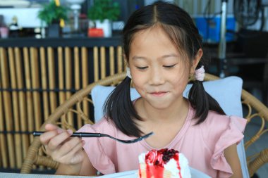 Kafede çilekli pasta yiyen Asyalı genç kızın portresi..