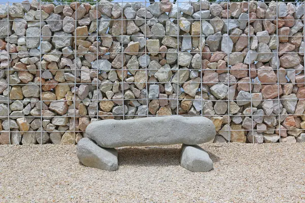 Close-up stone bench and stone wall with steel bar for background.