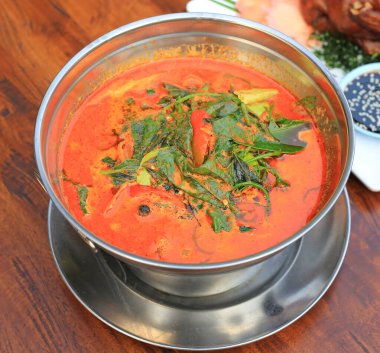 Ahşap masa arkasında alüminyum kâse içinde cha plu yaprağı ile Periwinkle köri. Lezzetli sıcak ve baharatlı Tayland yemekleri..