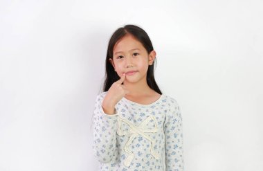 Yakışıklı Asyalı kız beyaz arka planda işaret parmağını ağzının köşesinde tutuyor. Vücudun bir kısmını işaret eden çocuk.