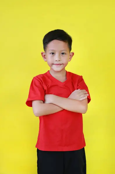 Stock image Portrait Asian little boy age about 7 years old standing and cross arms over chest looking straight at camera on yellow studio background.