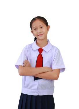 İlkokul üniformalı kendine güvenen Asyalı kız, göğsünün üzerinde çapraz kollarla duruyor ve beyaz arka planda izole edilmiş kameraya bakıyor. Kırpma yolu ile resim.