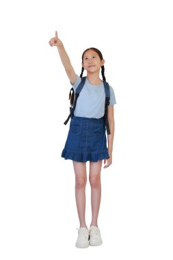 Sırt çantalı gülümseyen Asyalı kız çocuğu işaret parmağıyla beyaz arka planda izole edilmiş boş uzay duruşunu işaret ediyor. Kırpma yolu ile tam boy fotoğraf.