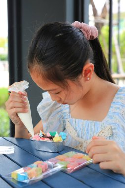 Pasta yapan ve dekore eden Asyalı kız çocuğu portresi..