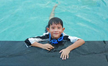 7 yaşındaki Asyalı bir çocuğun portresi havuzda yüzerken eğleniyor..