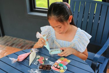 Asyalı kız çocuk kek pişirmeyi, pastayı süslemeyi sever..