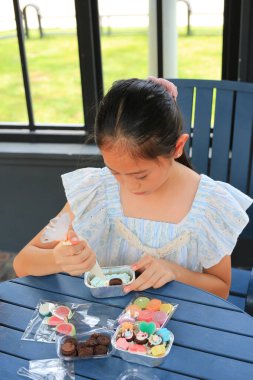 Asyalı kız çocuk kek pişirmeyi, jöle ve krema şekeri ile süslemeyi sever..