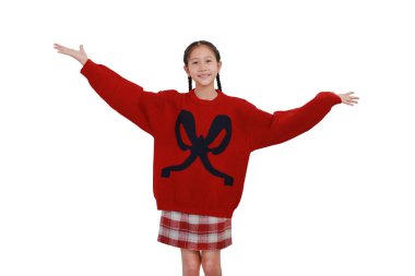 Çocuk beyaz arka planda dururken kollarını açtı. Yeni yılda mutlu Asyalı kız ve kış mevsiminde Noel kostümleri kalkıyor ve el kaldırıyor..