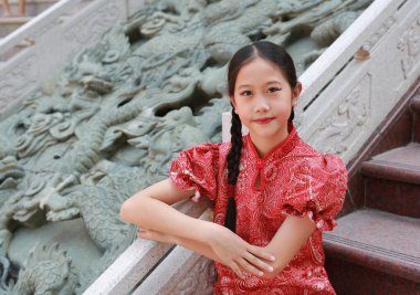 Portrait of beautiful Asian girl child in traditional dress celebrates Chinese new year. clipart